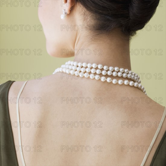 Rear view of woman wearing pearl necklace.