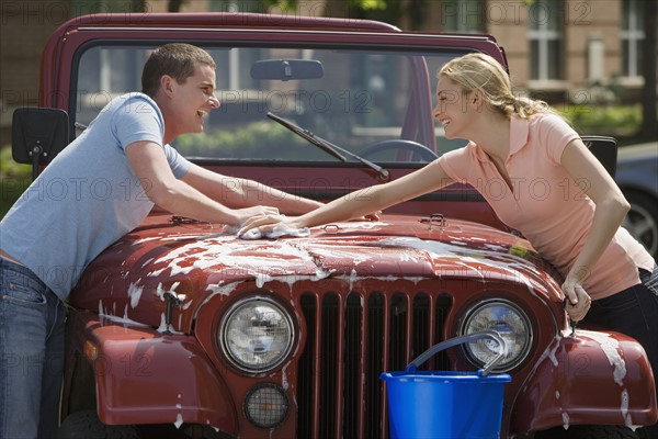 Couple washing jeep.