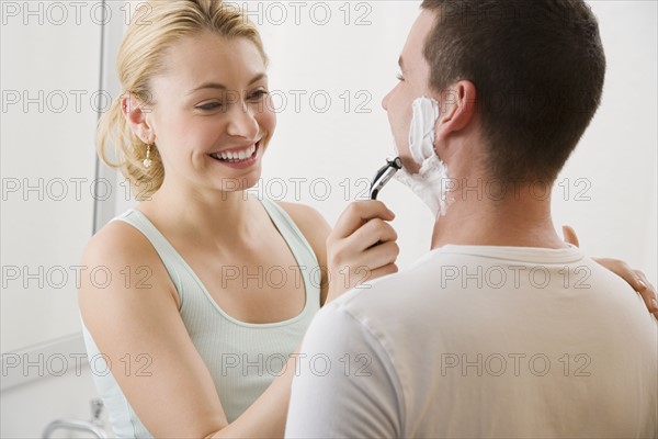 Woman shaving boyfriend’s face.