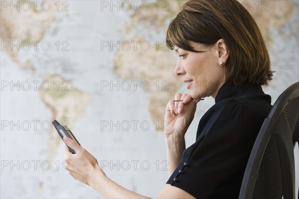 Businesswoman looking at electronic organizer.