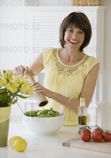 Woman grinding pepper onto salad.