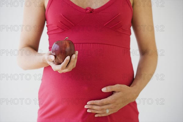 Pregnant woman holding apple.