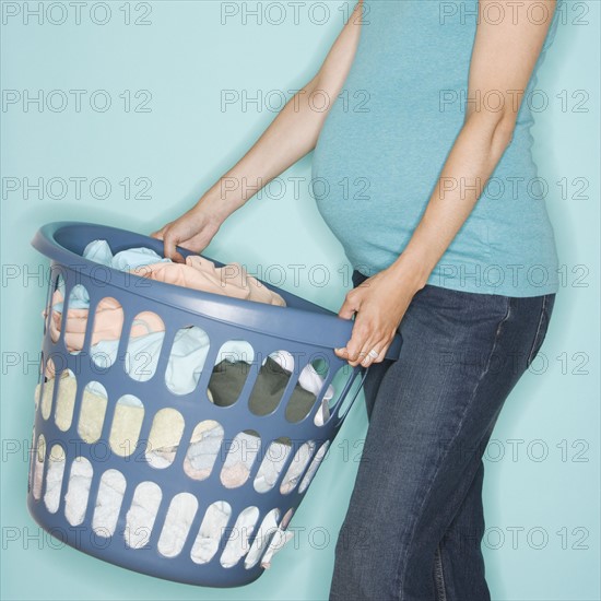 Pregnant woman carrying laundry basket.