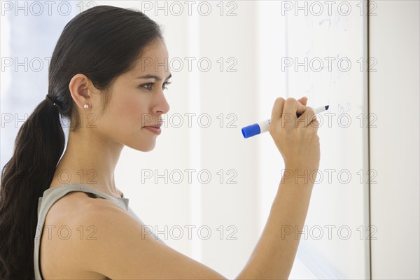 Businesswoman writing on dry erase board.