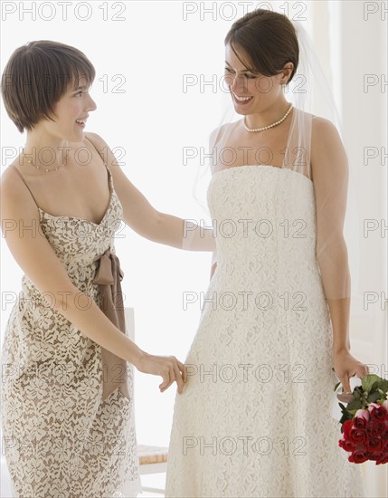 Bridesmaid adjusting bride’s veil.