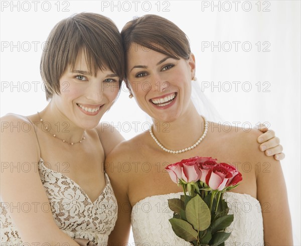 Bride and bridesmaid hugging.