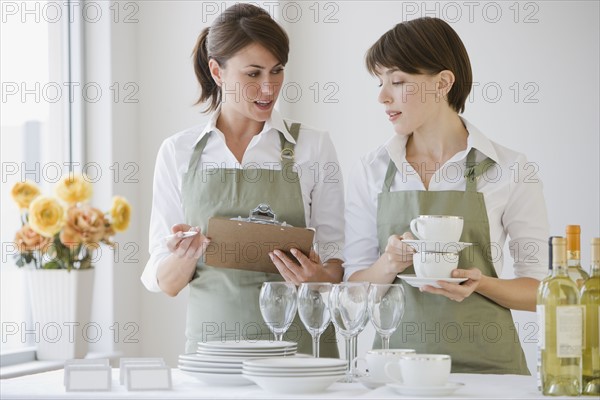 Two female caterers with dishware.