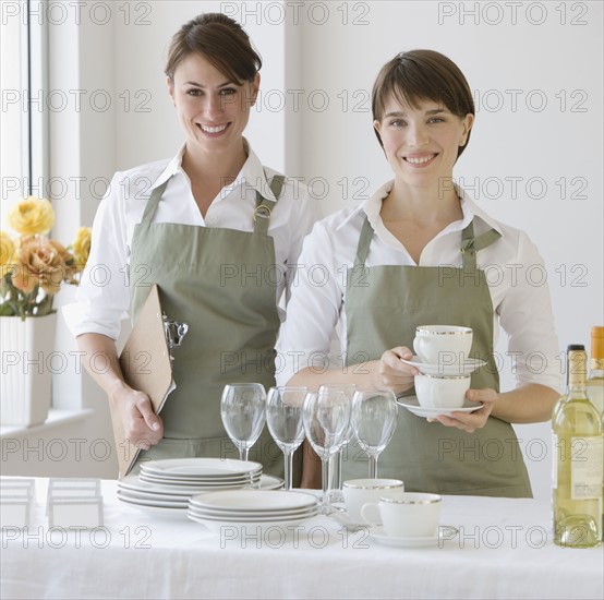 Two female caterers with dishware.