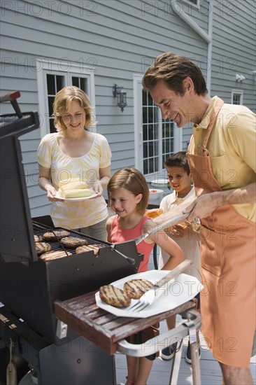 Family barbequing on deck.