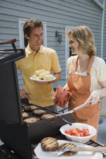 Couple barbequing on deck.