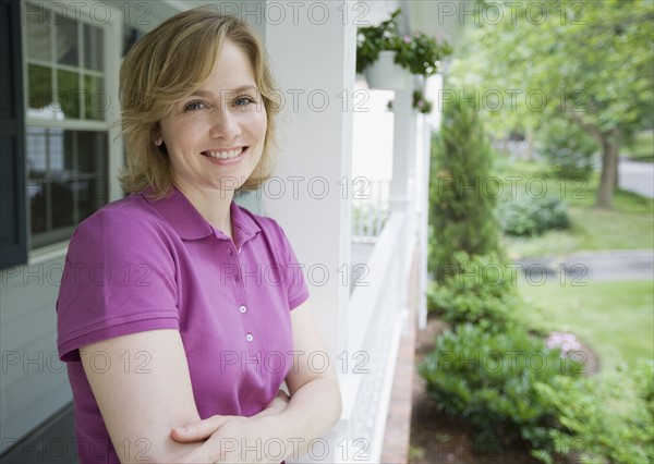 Woman leaning on porch railing.