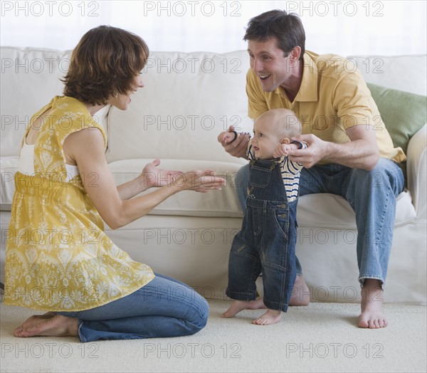 Parents helping baby walk.