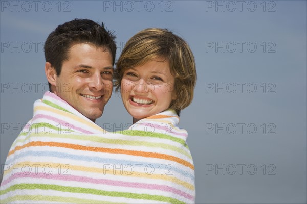 Couple wrapped in beach towel.