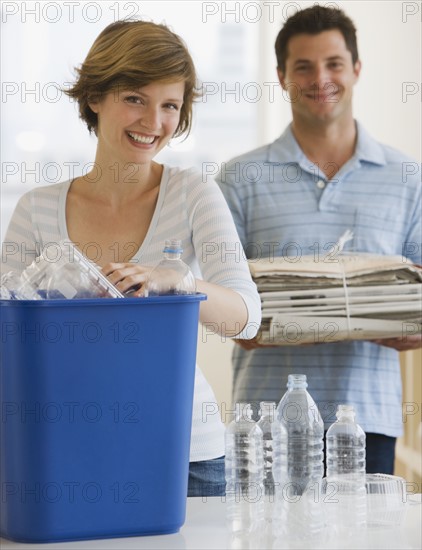 Couple recycling plastic and newspaper.