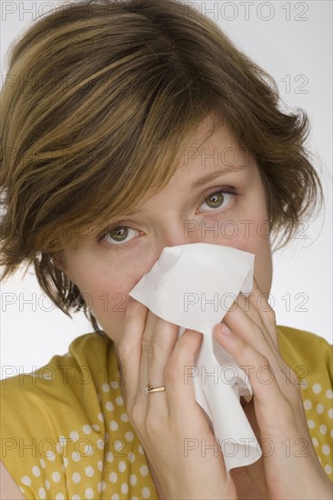 Close up of woman blowing nose.