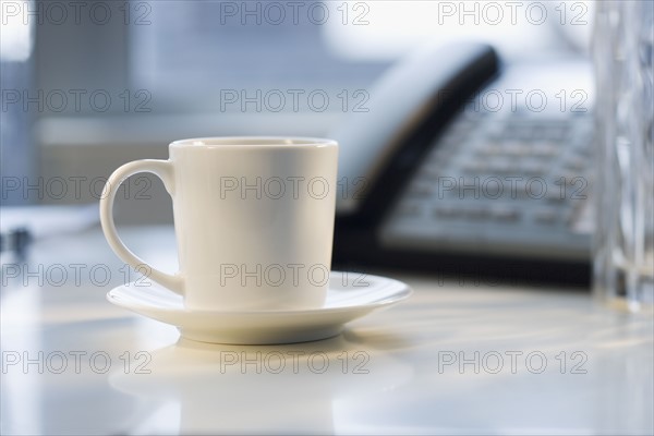 Coffee mug next to telephone.