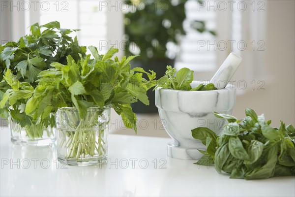 Fresh herbs next to mortar and pestle.