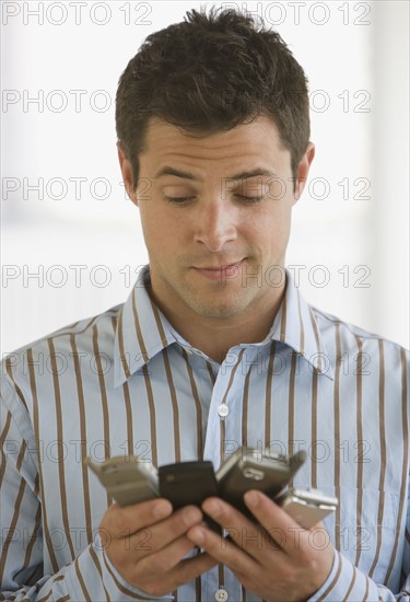 Man looking at multiple cell phones.