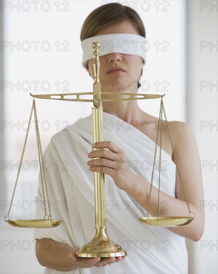 Blindfolded woman holding scales.