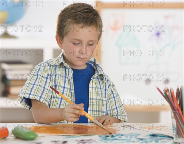 Boy painting at table.