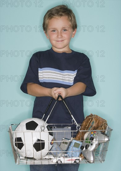 Boy holding shopping basket with toys.