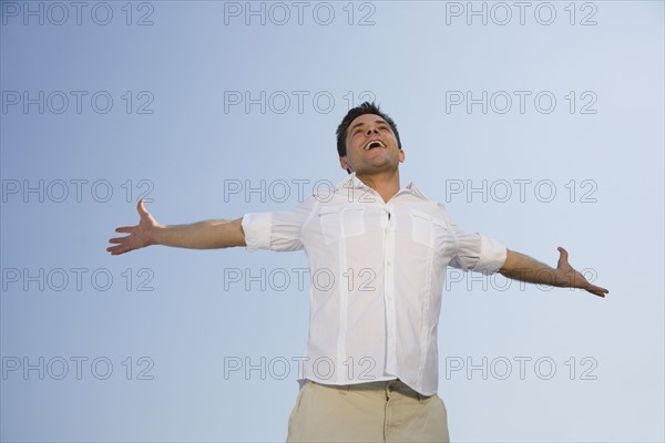 Low angle view of man with arms outstretched.