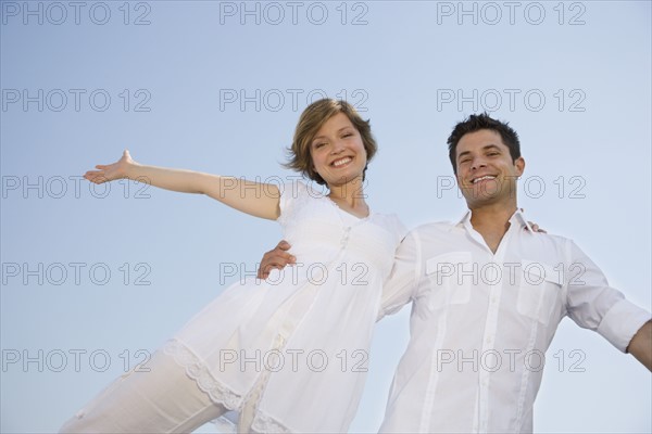 Low angle view of couple with arms outstretched.