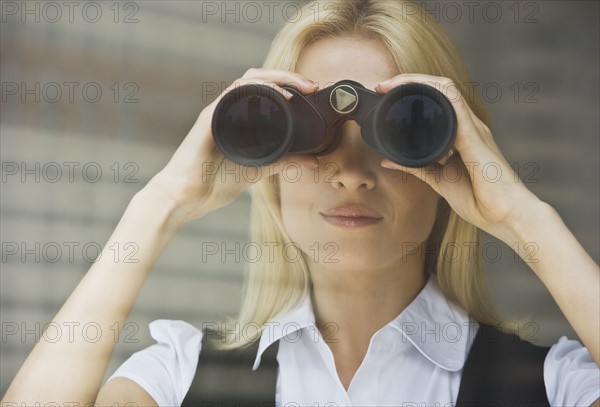 Businesswoman looking through binoculars.