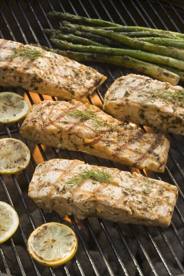 Fish and asparagus cooking on grill.