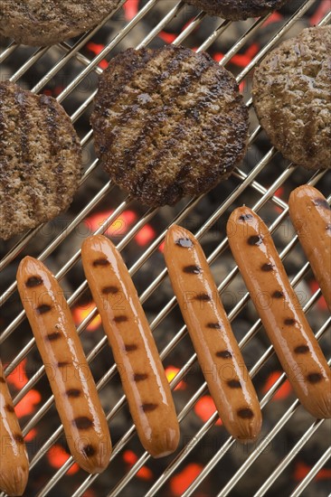 Hamburgers and hot dogs cooking on grill.