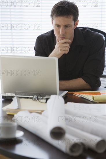 Male architect looking at laptop.