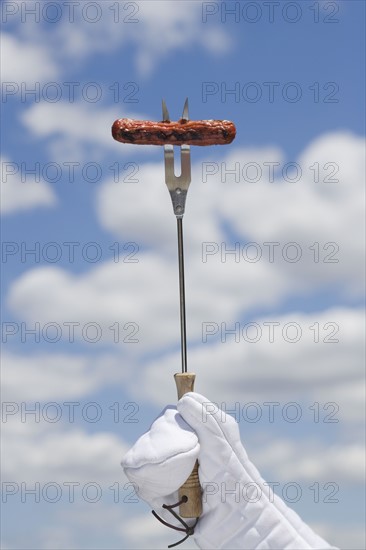 Hot dog on barbeque fork.