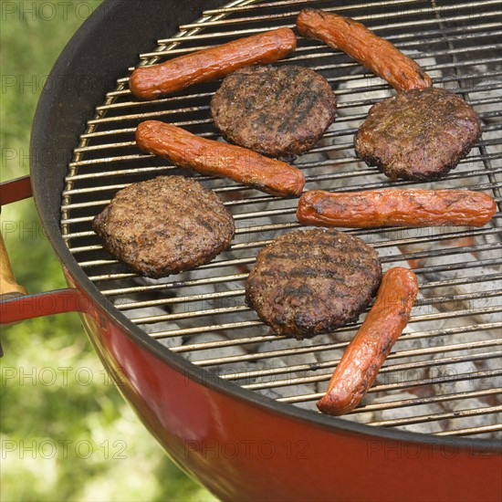 Hot dogs and hamburgers cooking on grill.