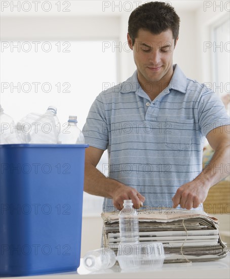 Man recycling newspaper and plastic.