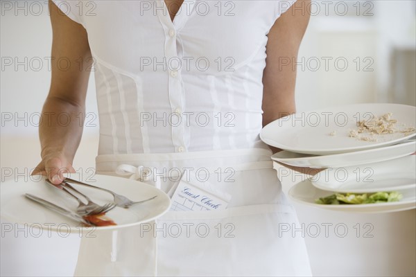 Waitress holding dirty plates.