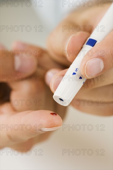 Person using blood sugar monitor on finger.