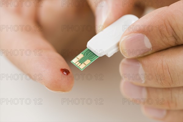 Person using blood sugar monitor on finger.