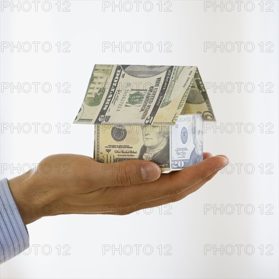 Businessman holding house made money.