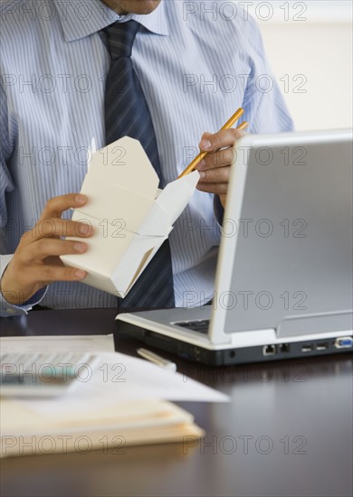 Businessman eating take out at desk.