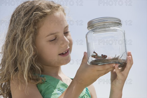 Girl looking at reptile in jar.