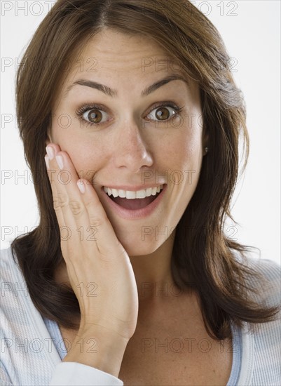 Woman looking surprised with hand on cheek.