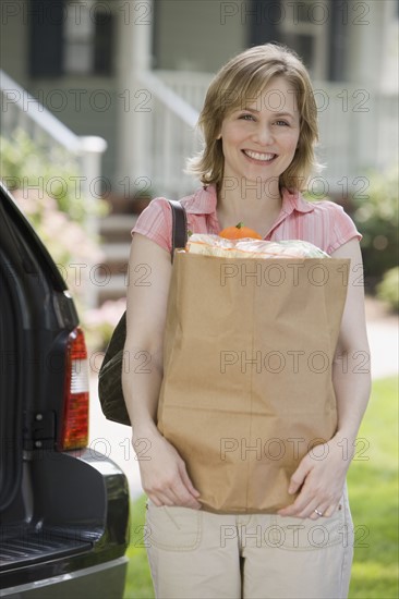 Woman holding bag of groceries.