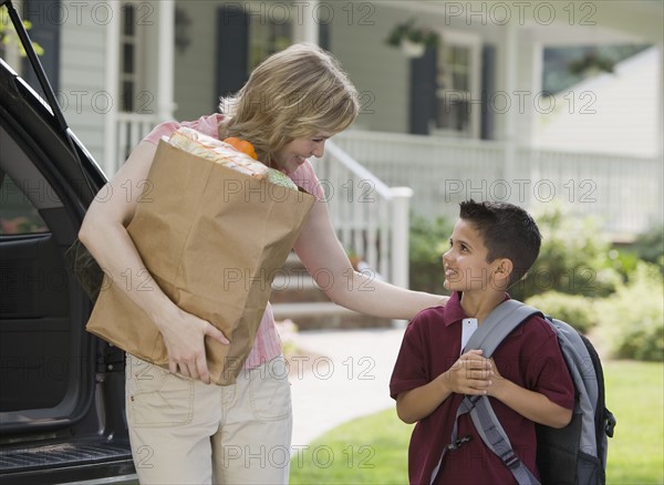 Mother holding groceries and smiling at son.