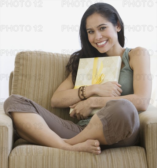 Woman hugging gift on chair.