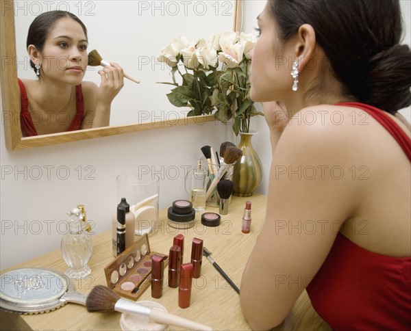 Woman applying makeup in mirror.