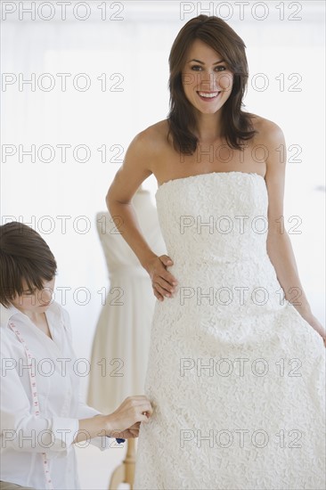 Bride having dress fitted.