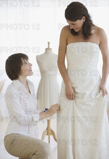 Bride having dress fitted.