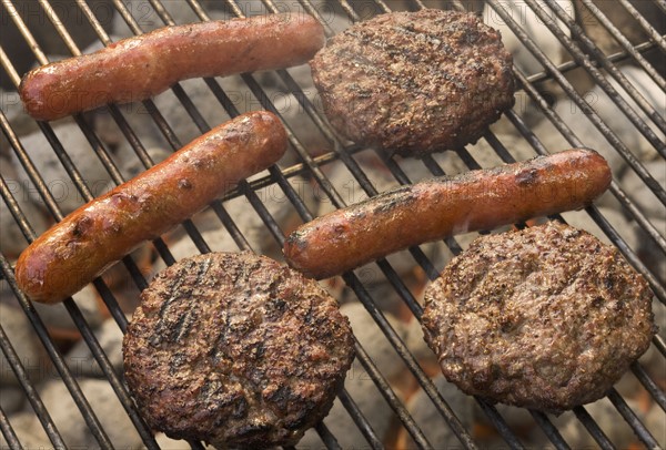 Hot dogs and hamburgers cooking on grill.