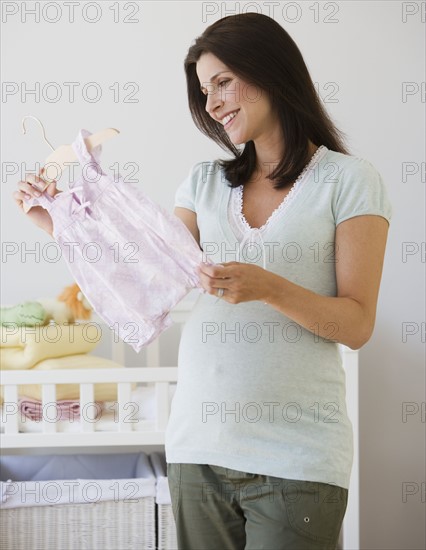 Pregnant woman looking at baby clothes.