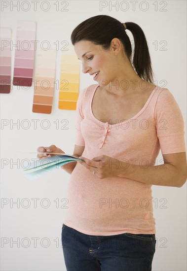 Pregnant woman looking at paint swatches.